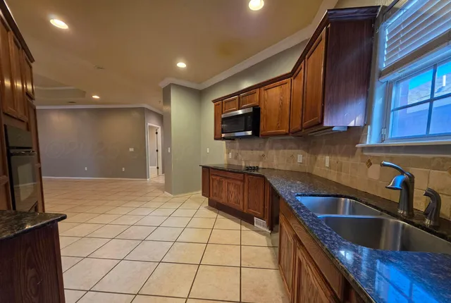 a kitchen with stainless steel appliances granite countertop a sink a stove and a microwave with wooden cabinets