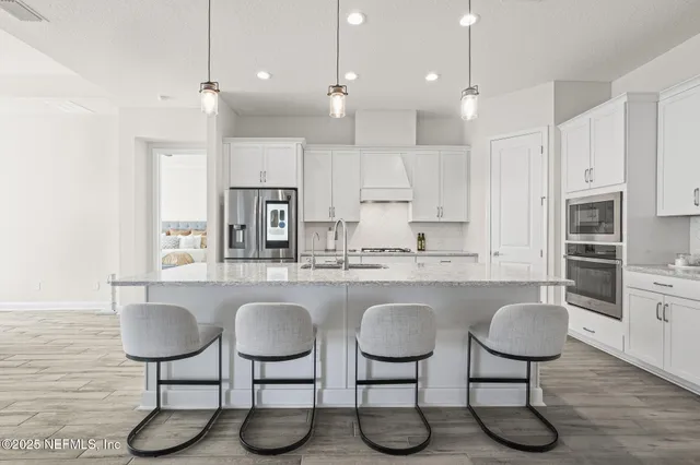 a large white kitchen with kitchen island a stove a sink a center island and wooden floor