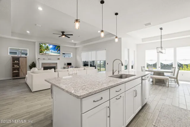 a kitchen with stainless steel appliances granite countertop a table chairs stove a sink dishwasher and white cabinets with wooden floor