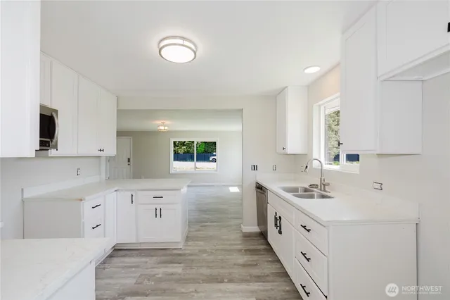 a large white kitchen with stainless steel appliances granite countertop a sink and cabinets