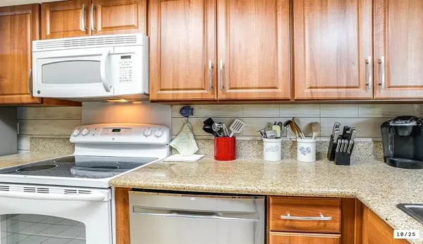 a kitchen with granite countertop white cabinets and white appliances