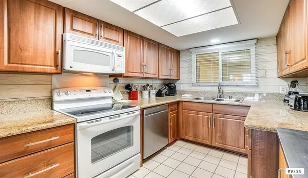 a kitchen with granite countertop cabinets stainless steel appliances a sink and a window