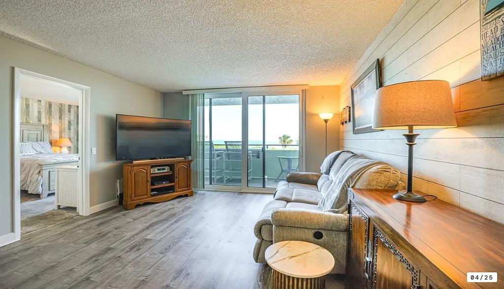 6009 Sea Ranch Drive, Unit 208 Hudson, FL 34667 - Photo 9 of 22 a living room with furniture a flat screen tv and a floor to ceiling window