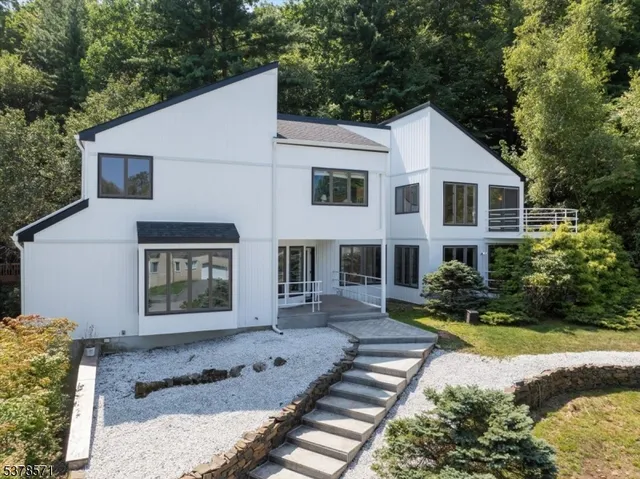 a view of a white house next to a yard with potted plants