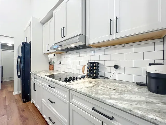 a large kitchen with stainless steel appliances kitchen island granite countertop a refrigerator a sink dishwasher a stove and a dining table with wooden floor