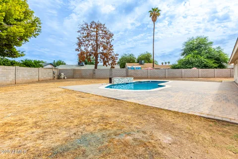 a swimming pool with outdoor seating and yard in the back
