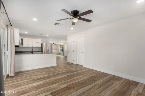 a view of empty room with wooden floor and ceiling fan