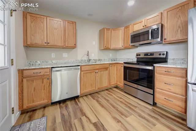 a kitchen with granite countertop white cabinets stainless steel appliances and a sink