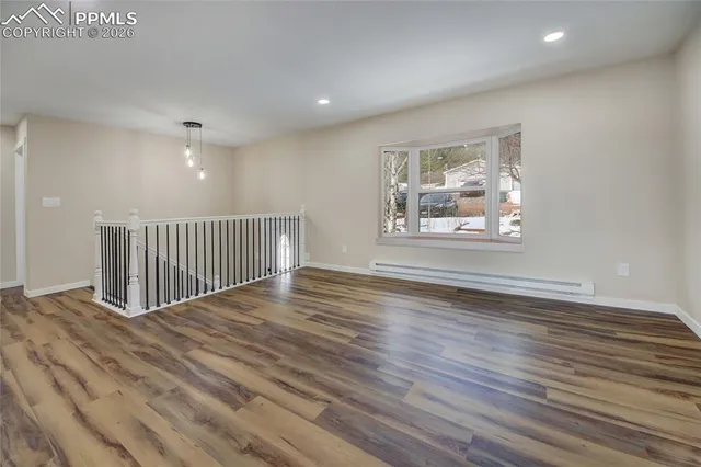 a view of an empty room with wooden floor and a window