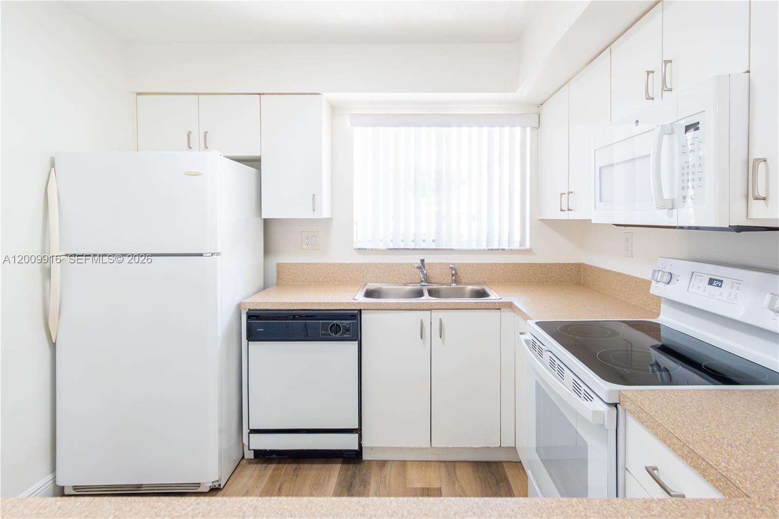 14905 Southwest 80th Street, Unit 212 Miami, FL 33193 - Photo 27 of 37 a kitchen with a sink a refrigerator and cabinets