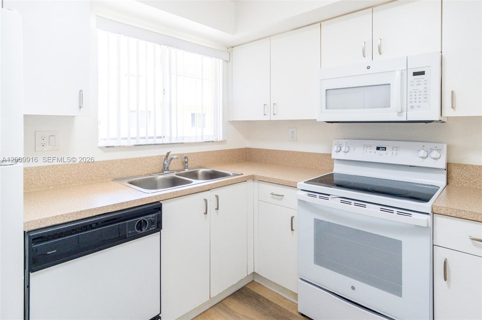 14905 Southwest 80th Street, Unit 212 Miami, FL 33193 - Photo 28 of 37 a kitchen with cabinets appliances a sink and a window