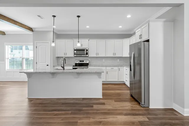 a kitchen with stainless steel appliances granite countertop a refrigerator a sink a stove and white cabinets with wooden floor