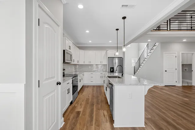 a view of a kitchen with kitchen island stainless steel appliances refrigerator stove and wooden floor