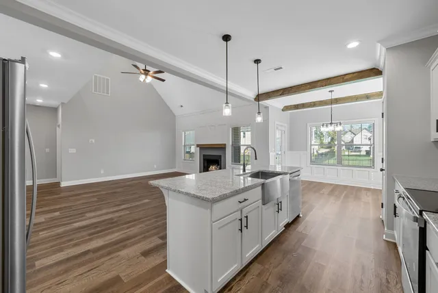 a large kitchen with kitchen island a stove a sink dishwasher and a fireplace with wooden floor