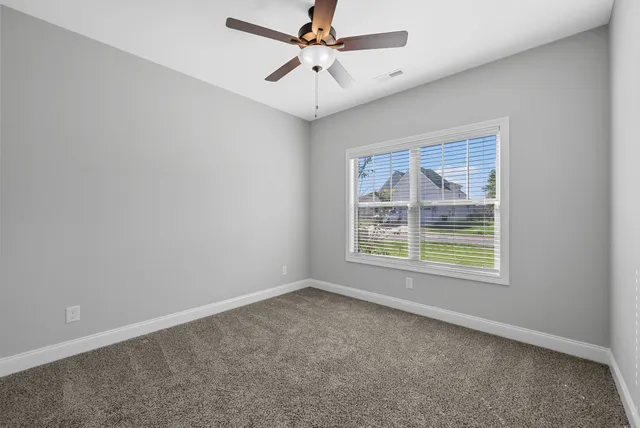 an empty room with windows and ceiling fan