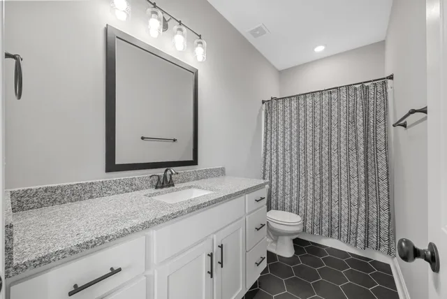 a bathroom with a granite countertop sink a toilet and a mirror