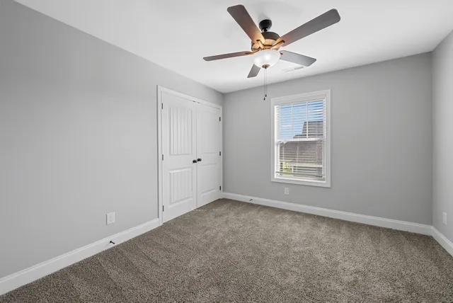 an empty room with a window and a ceiling fan