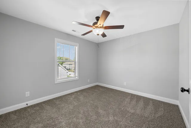 an empty room with windows and fan