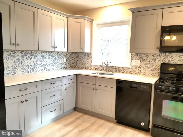 a kitchen with white cabinets sink and stove