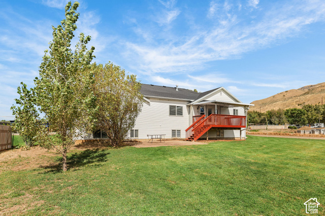 1045 West 3600th South Perry, UT 84302 - Photo 46 of 57 White siding exterior with a dark shingle roof, complemented by a red-painted elevated deck featuring a staircase