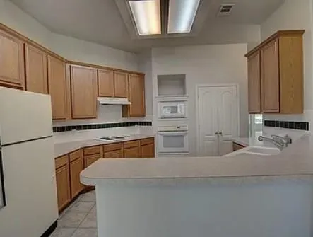 a kitchen with stainless steel appliances granite countertop a refrigerator sink and white cabinets