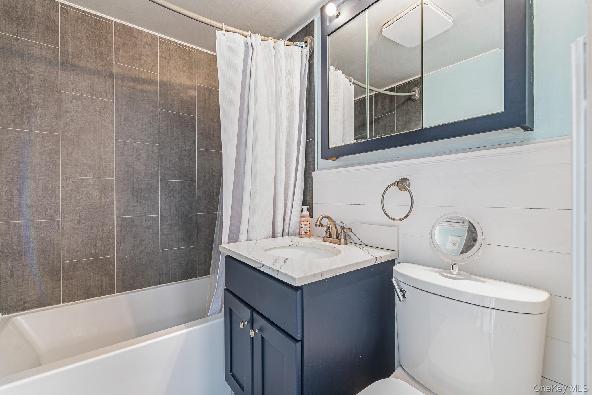 33 Lillian Road Nesconset, NY 11767 - Photo 22 of 42 The Beautifully Upgraded Full/Guest Bathroom Offers A Full Bathtub with All Floor To Ceiling Fully Ceramic Tiled Walls/Tub Surround (All Large/Oversized Ceramic Tile), Shiplap Accent Walls, Ceramic Tiled Floor, And An Upgraded Vanity, Medicine Cabinet & Fixtures.