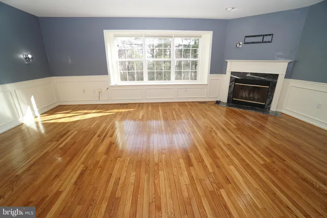 a view of empty room with wooden floor and fireplace