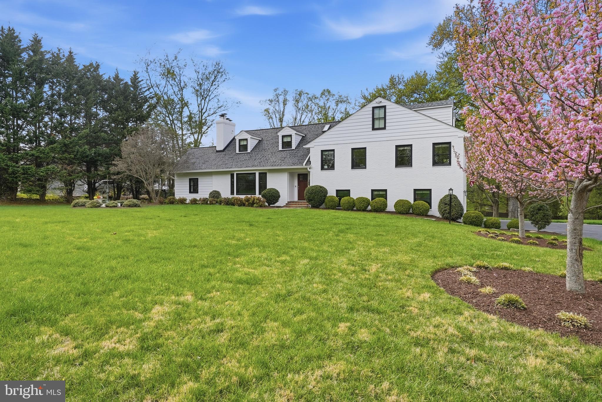 10712 Lockland Road Potomac, MD 20854 - Photo 5 of 66 a view of a white house in front of a big yard with plants and large trees