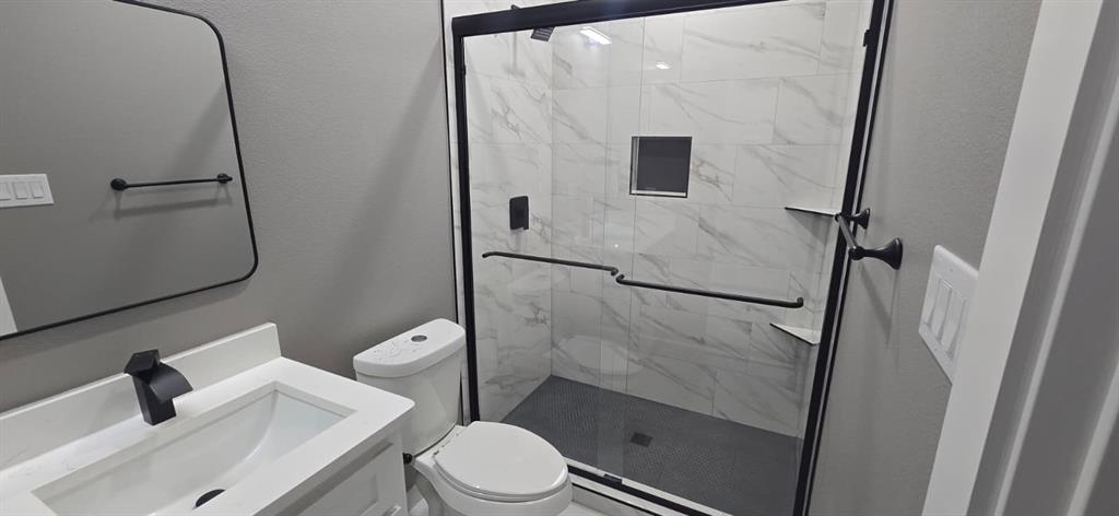 805 Fletcher Street Gainesville, TX 76240 - Photo 14 of 21 a white toilet sitting next to a bathroom sink