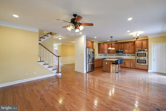 a kitchen with stainless steel appliances granite countertop a refrigerator a stove a sink dishwasher a dining table and chairs with wooden floor