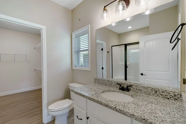 a bathroom with a granite countertop sink a toilet and a mirror