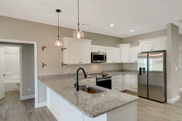 a kitchen with stainless steel appliances granite countertop a sink a refrigerator and a granite counter tops
