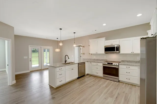 a large kitchen with stainless steel appliances granite countertop a stove and a sink