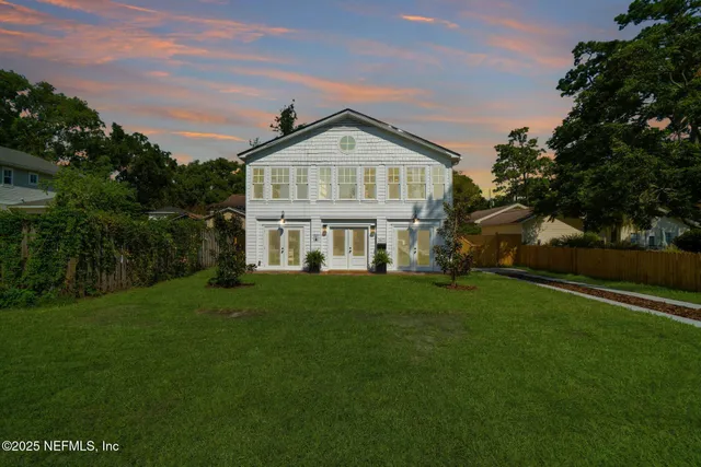 a view of a big house with a big yard and large trees