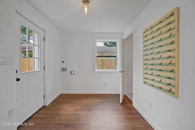a view of an empty room with window and wooden floor