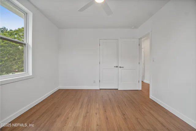 an empty room with wooden floor and windows