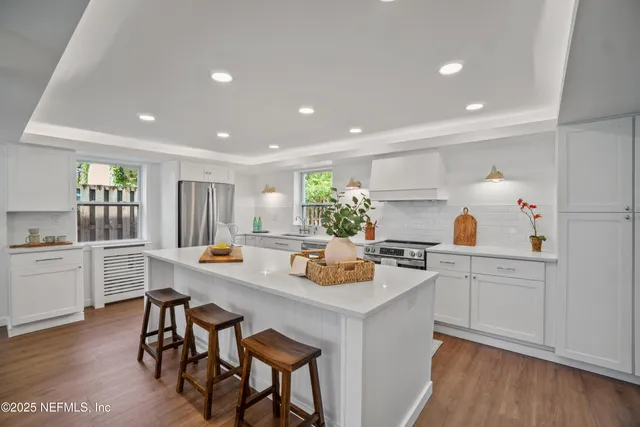 a kitchen with a dining table chairs sink and white cabinets