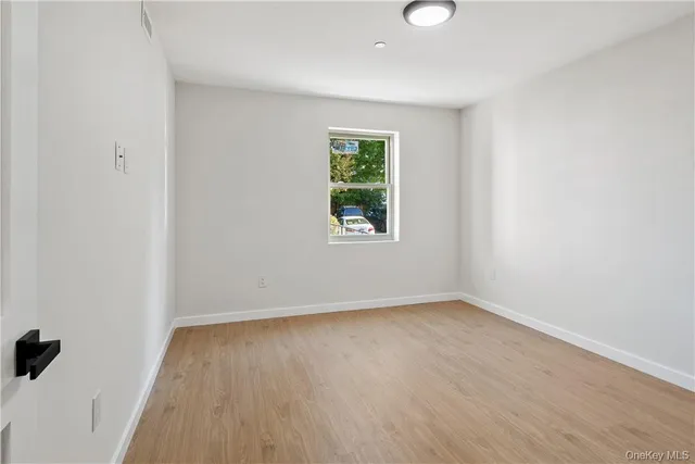 an empty room with a window and a wooden floor