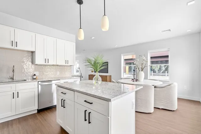 a kitchen with stainless steel appliances granite countertop a sink a stove and white cabinets with wooden floor