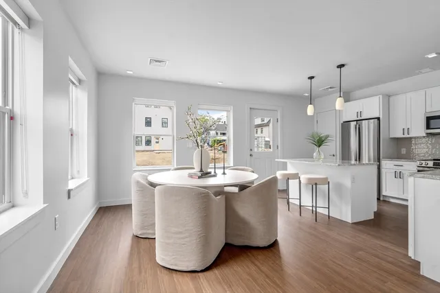 a view of kitchen with stainless steel appliances granite countertop a white cabinets and wooden floor