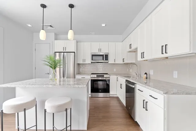 a kitchen with stainless steel appliances granite countertop a sink a stove a refrigerator and island with wooden floor