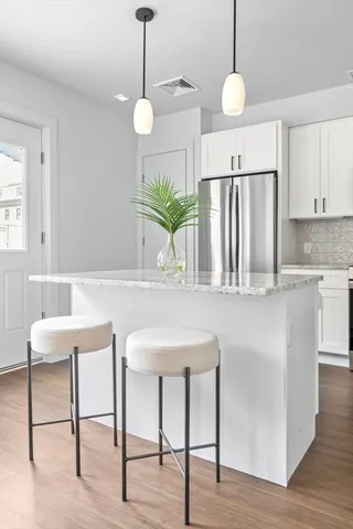 a kitchen with stainless steel appliances granite countertop a table chairs and white cabinets