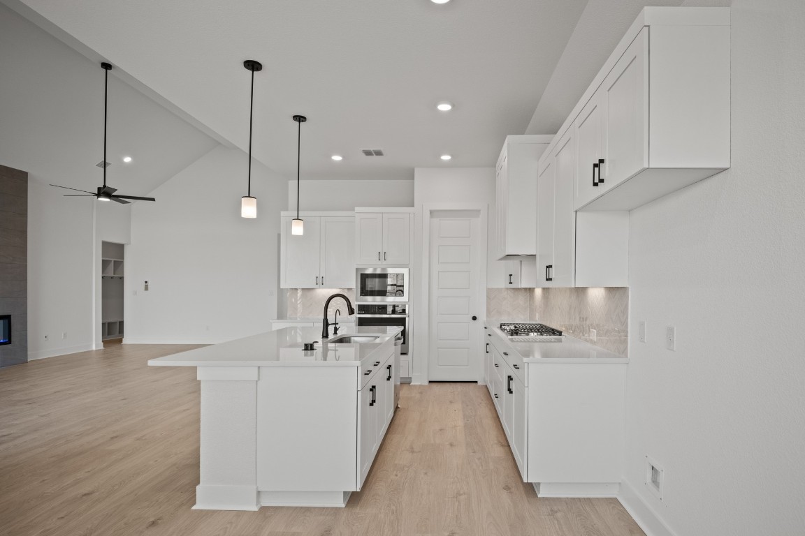 245 Begonia Street Buda, TX 78610 - Photo 7 of 21 a large white kitchen with a sink a counter top space stainless steel appliances and a center island