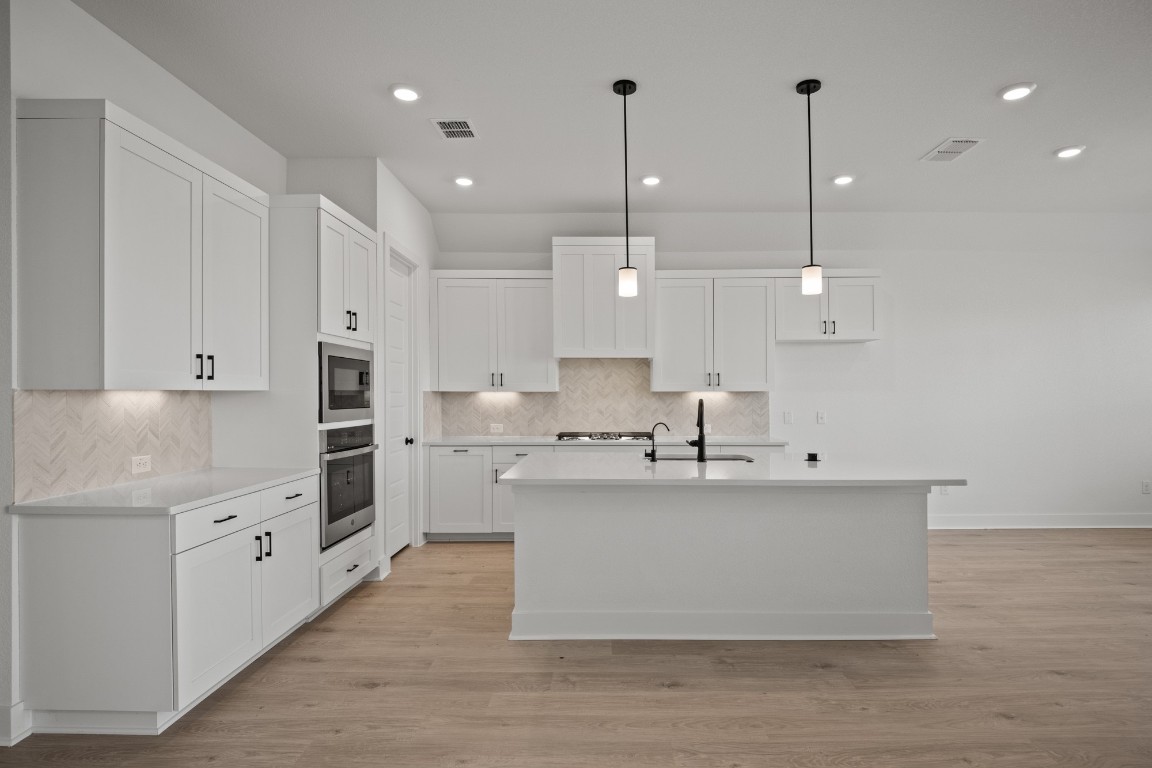 245 Begonia Street Buda, TX 78610 - Photo 8 of 21 a large kitchen with stainless steel appliances a large counter top a stove a sink and a refrigerator