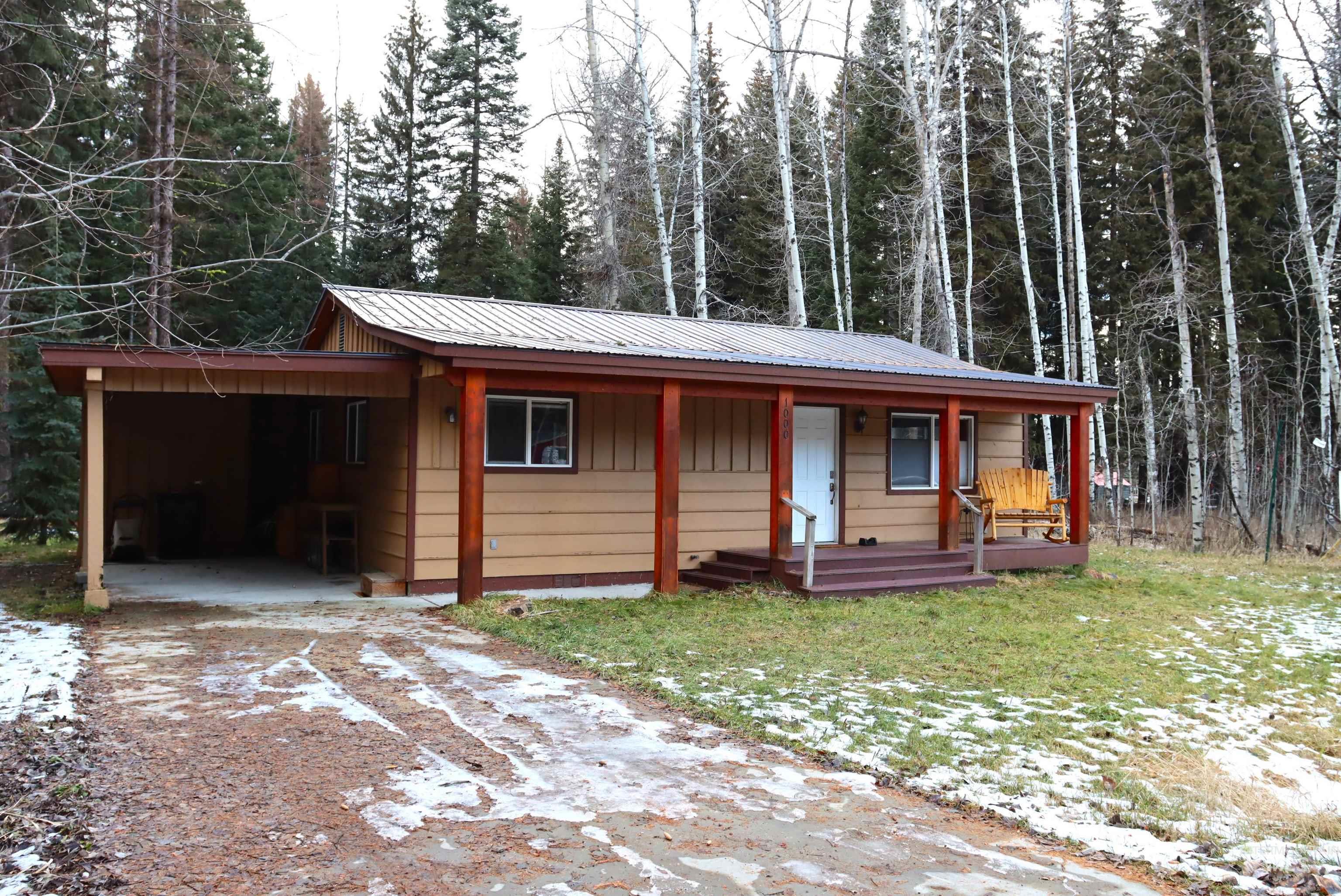 View of front of house with crawl space, a metal roof, a porch, an attached carport, and driveway