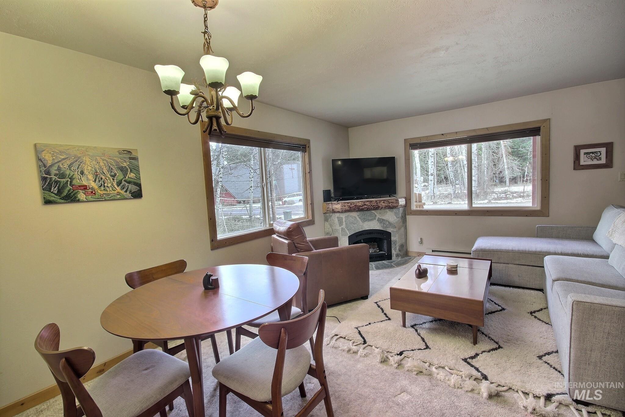 1000 Gamble Road McCall, ID 83638 - Photo 6 of 15 Dining space with a fireplace, healthy amount of natural light, a chandelier, and baseboard heating