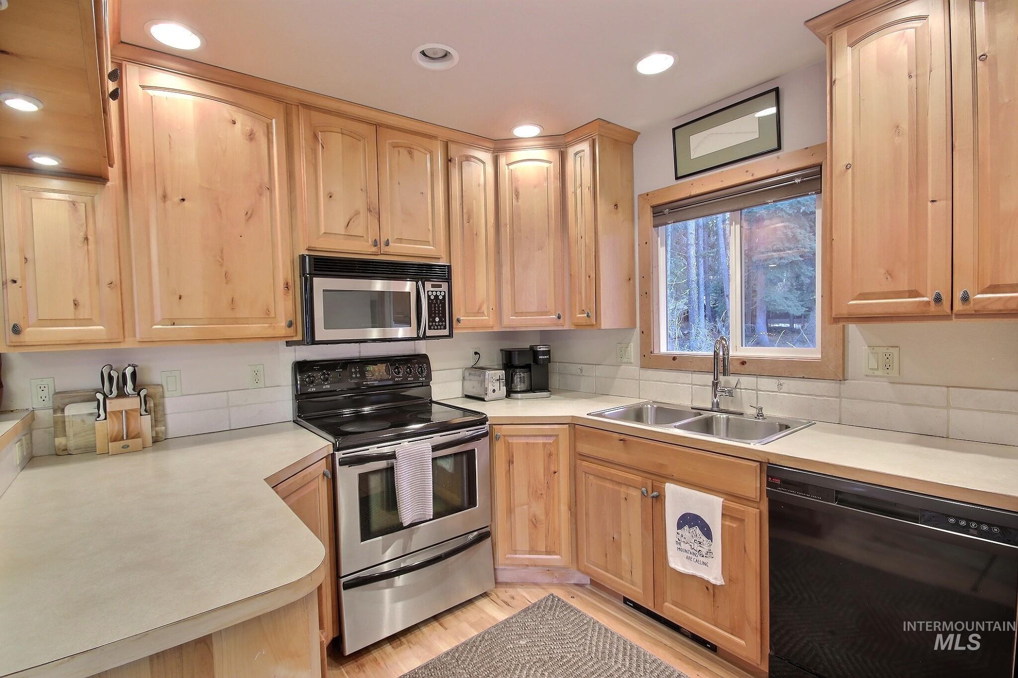1000 Gamble Road McCall, ID 83638 - Photo 8 of 15 Kitchen featuring stainless steel appliances, light countertops, light brown cabinetry, light wood-type flooring, and recessed lighting