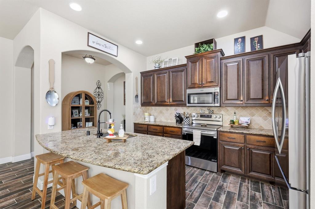 324 Sherbrook Street Van Alstyne, TX 75495 - Photo 7 of 27 a kitchen with stainless steel appliances granite countertop a stove top oven a sink dishwasher and cabinets with wooden floor