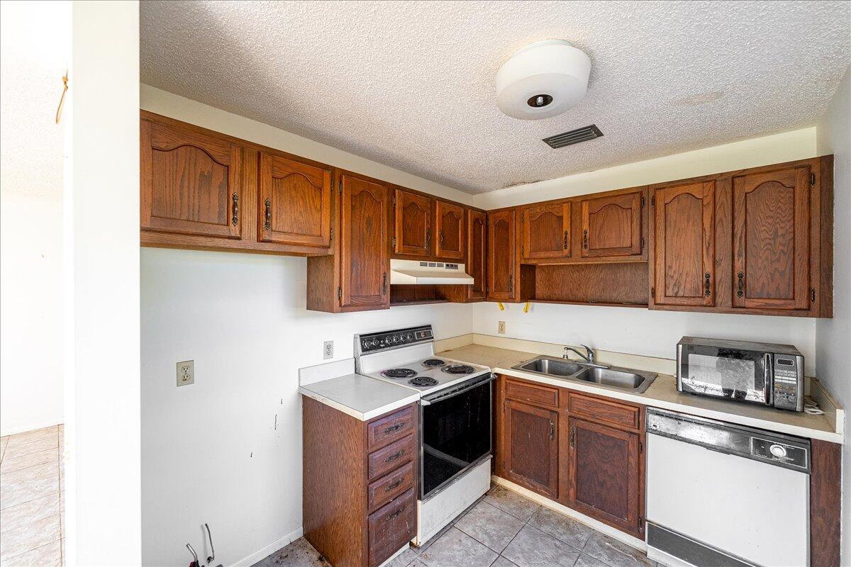 28 Lake Vista Trail, Unit 105 Port St. Lucie, FL 34952 - Photo 6 of 26 a kitchen with granite countertop a stove sink and cabinets
