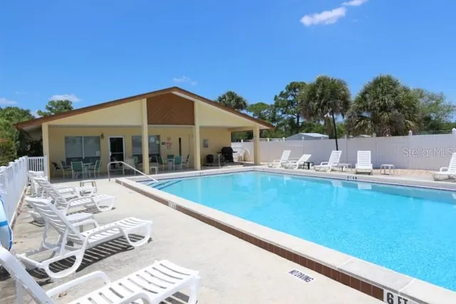 a view of a patio with couches table and chairs under an umbrella with large trees